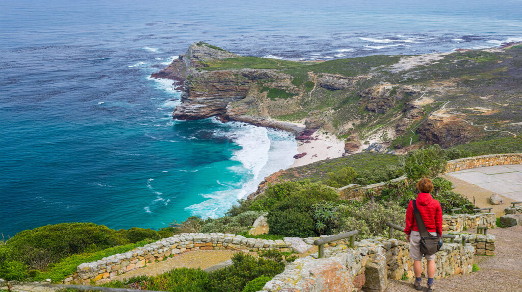 The image shows a tourist hiking at Cape Point