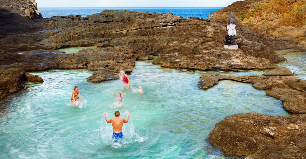 a family swimming in a natural rock pool at Angel's Billabong